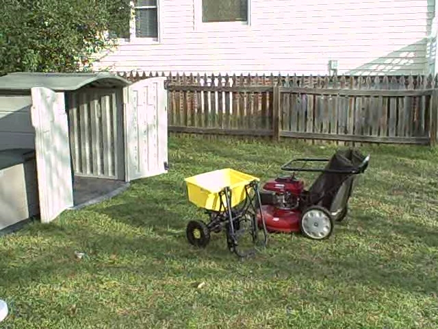 a mower next to a cart with a yellow cart sitting in front of it