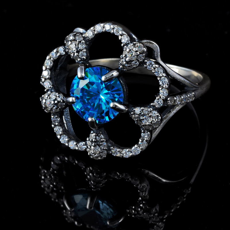 the blue diamond ring is set on top of the black surface