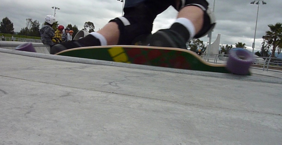 a skateboarder in black shorts and black shorts, rides on top of his board