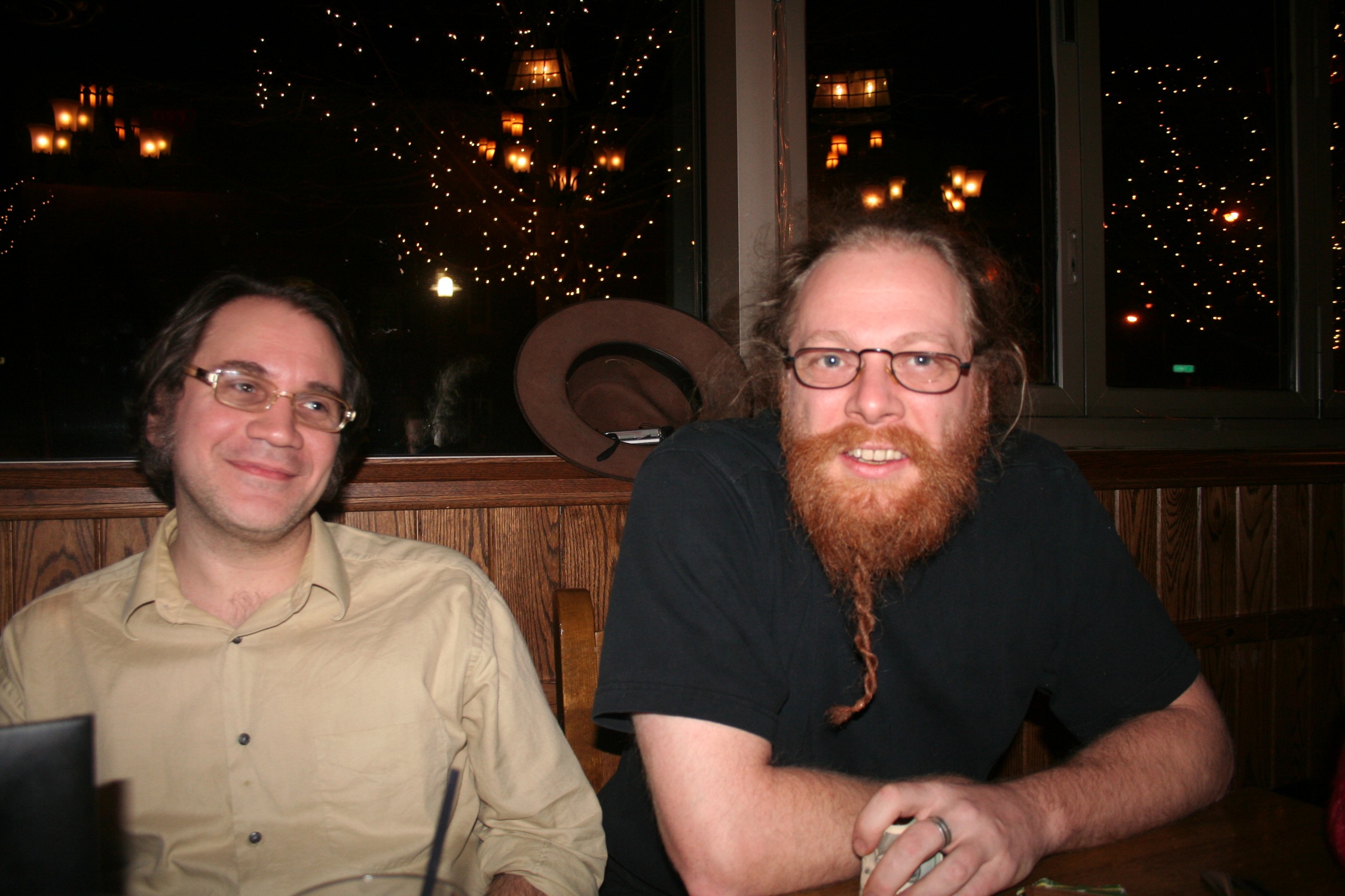 two men sitting at a table in a pub in front of some lights