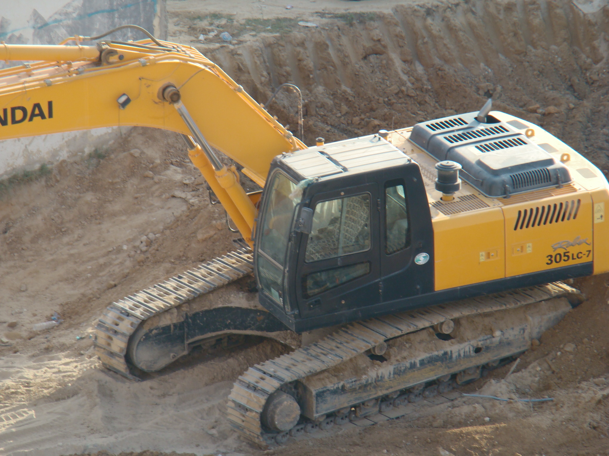 a yellow and black bulldozer sits next to a dirt mound