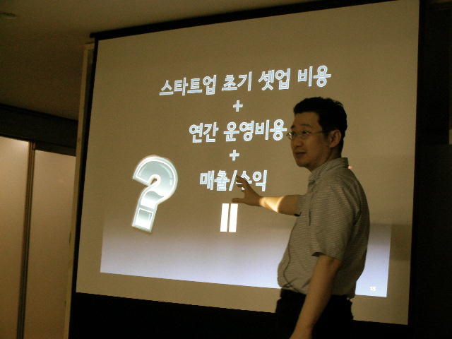a young man standing in front of a projection screen pointing