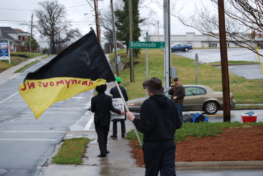 two people walking down the sidewalk with a flag