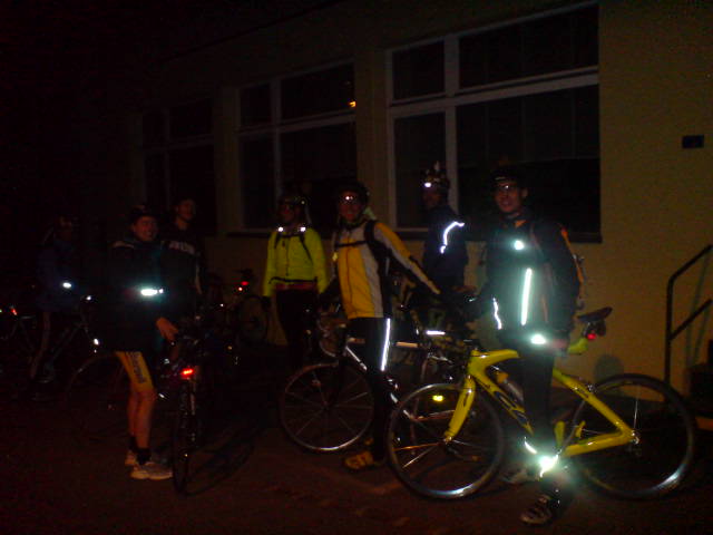 a group of bicyclists and their bikes on a dark street