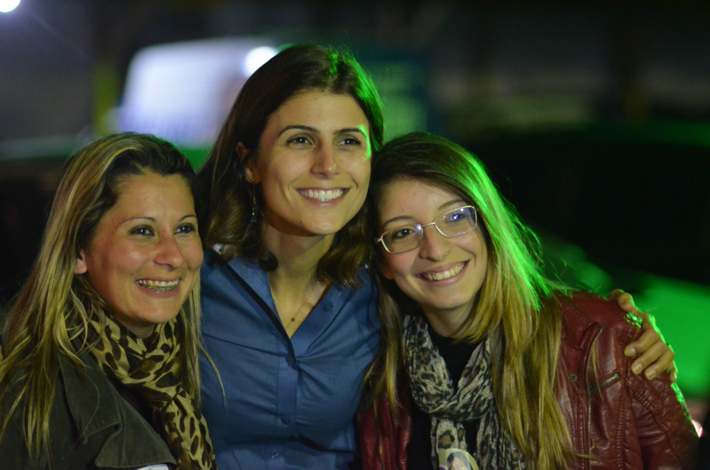 three smiling women pose for a po at night