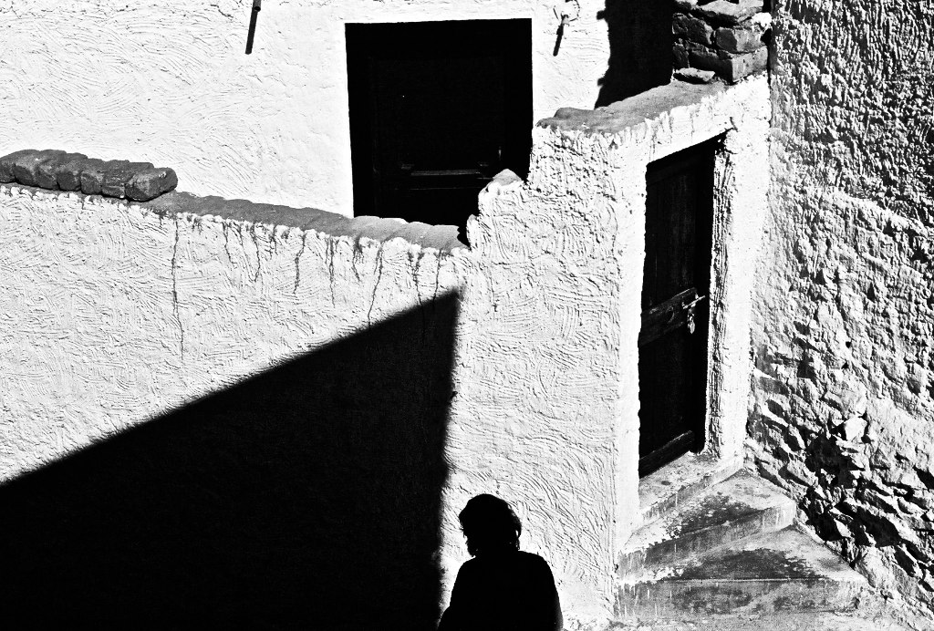 a man in the shadows looking at a building