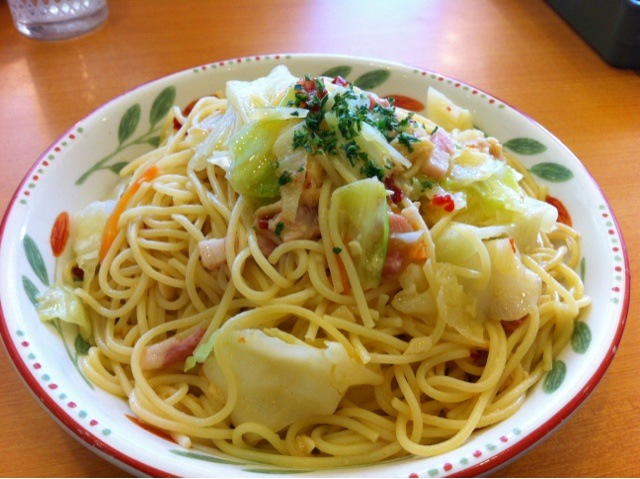 a plate filled with noodles and vegetables on top of a wooden table