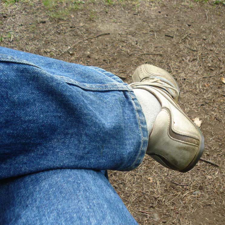 the foot of a person wearing blue jeans and a brown shoe
