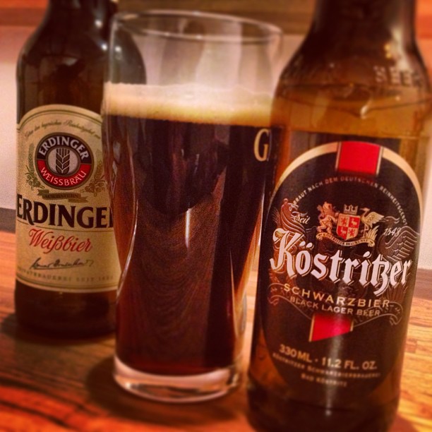 two bottles of kostridger and a glass filled with beer on a table