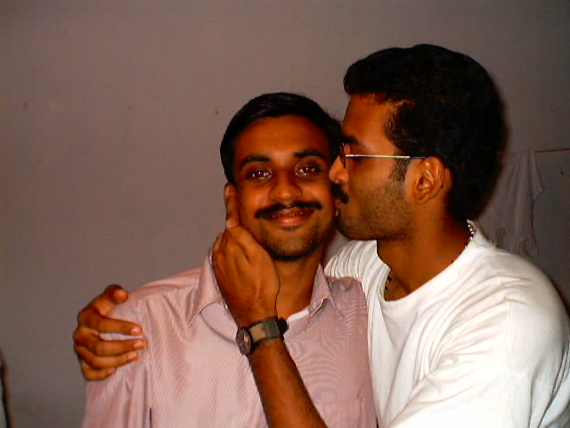 two men standing together and one is kissing the other