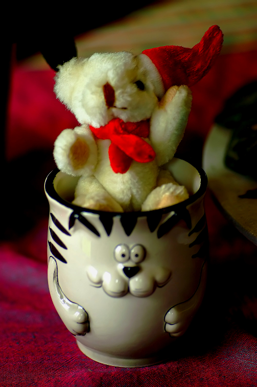 a white bear in a tiny cup with a red bow
