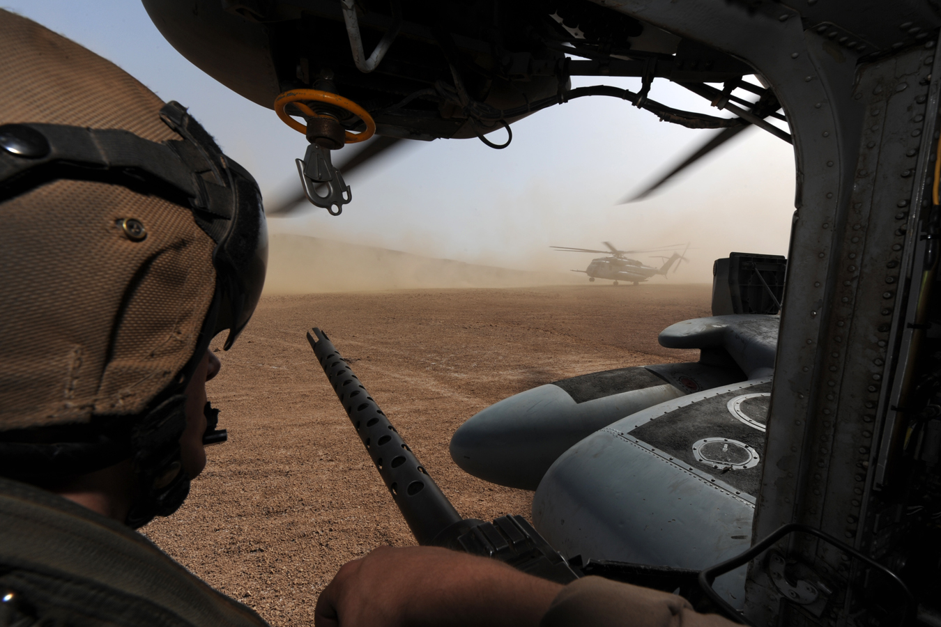 two pilots look out the window from inside an army helicopter