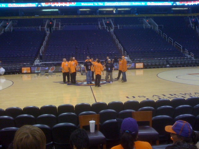a group of people in orange shirts standing on a basketball court