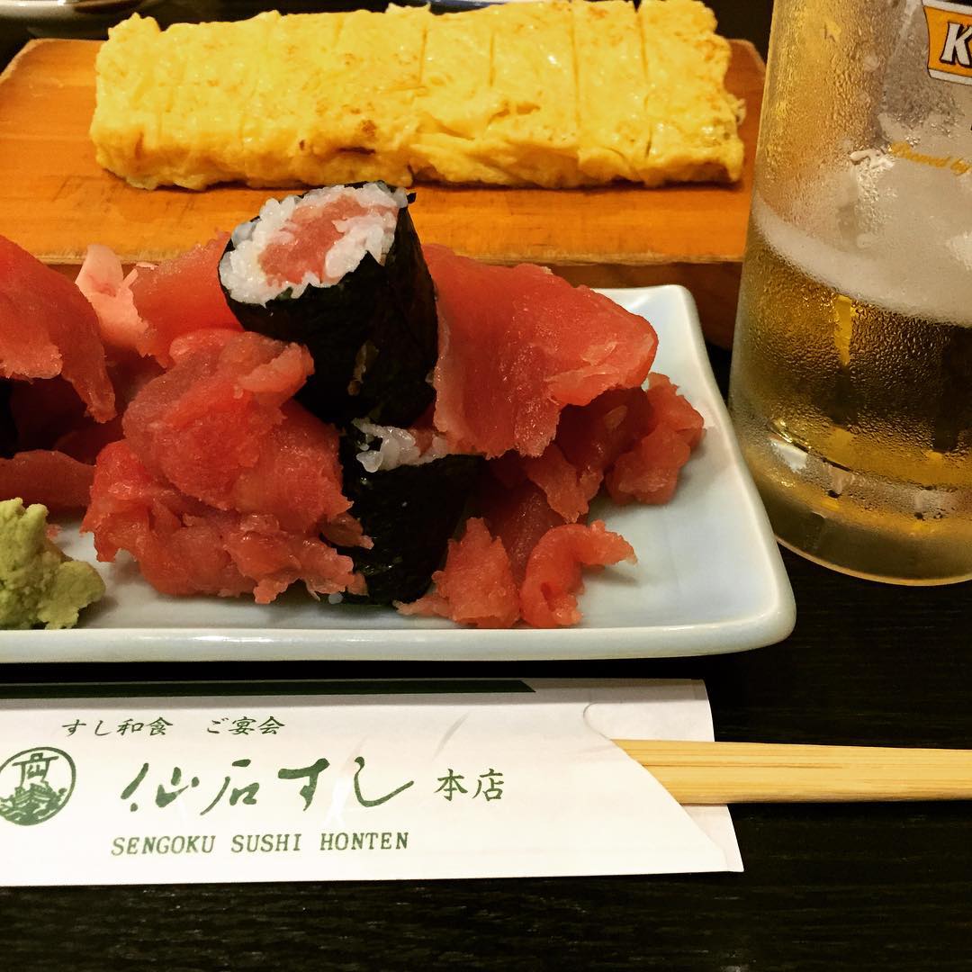a plate with sushi on it next to a glass of beer
