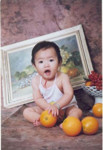 the young child is holding some oranges and posing for the camera