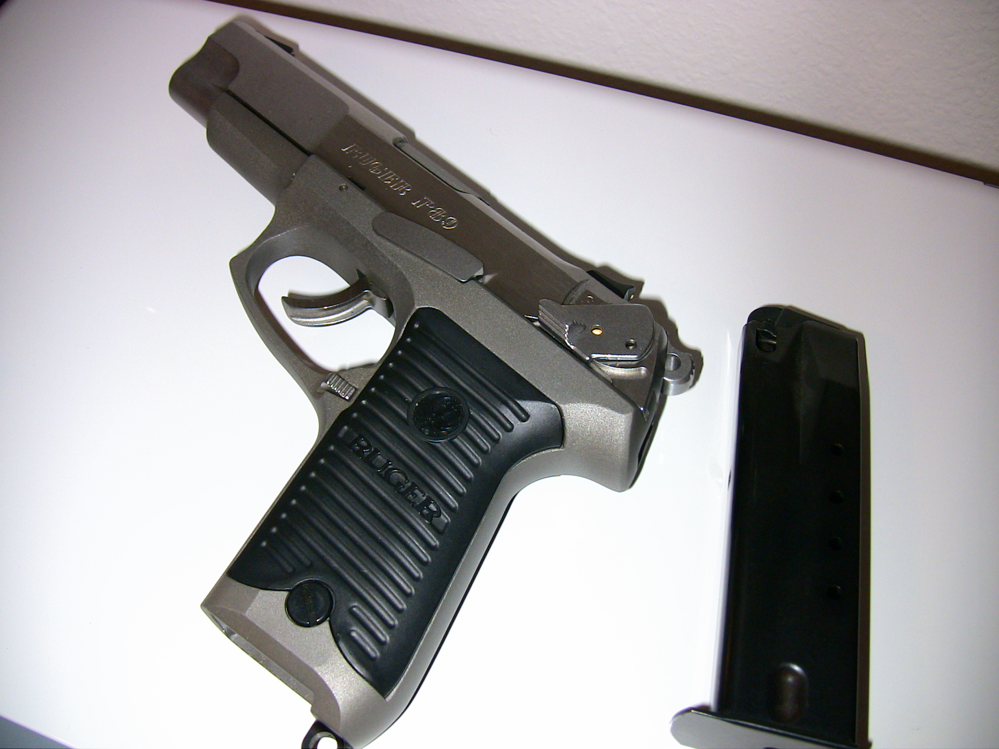 a gun lying on a white surface next to a device
