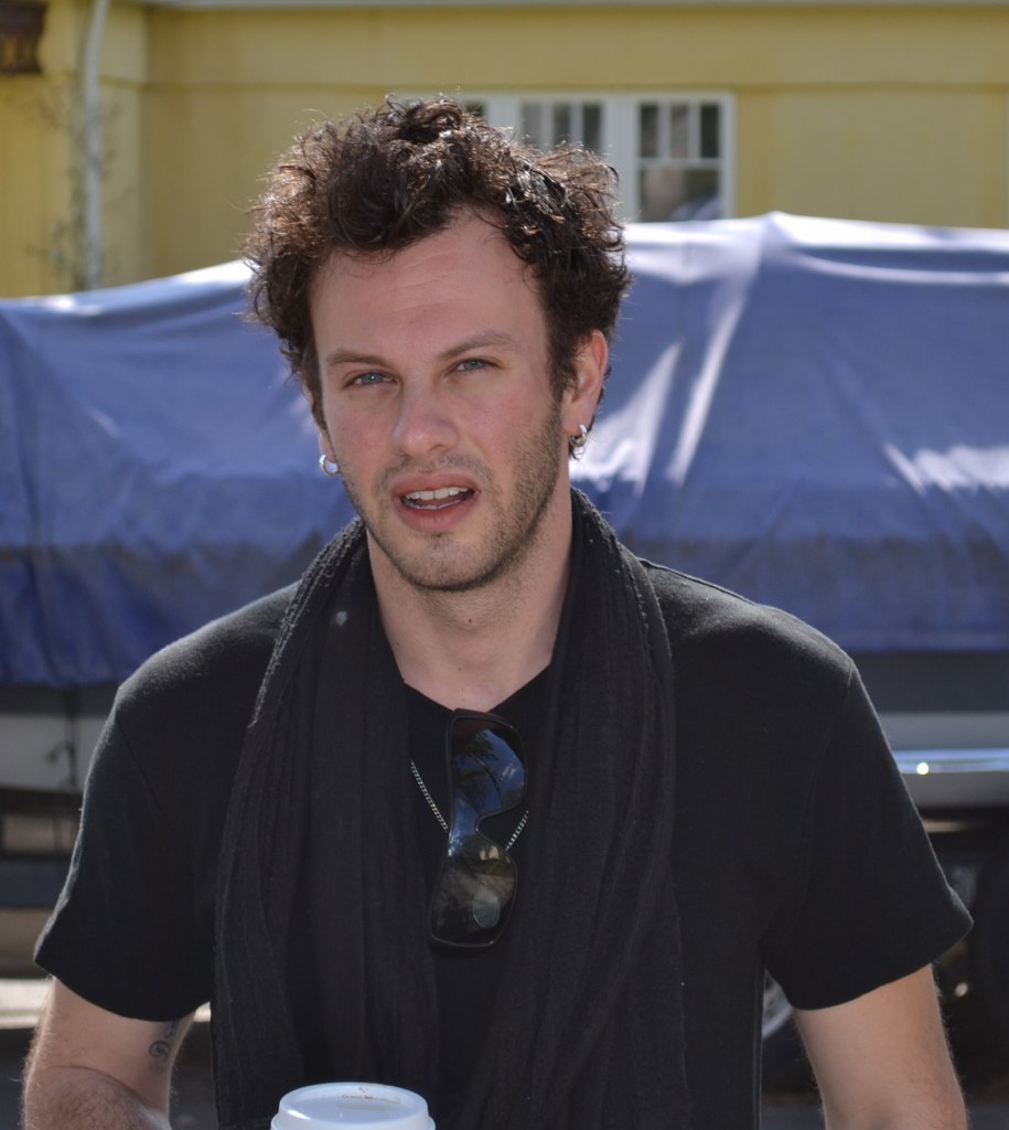 a man holding a cup while wearing a black t - shirt