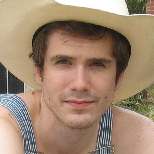 a shirtless man in a cowboy hat smiles for the camera