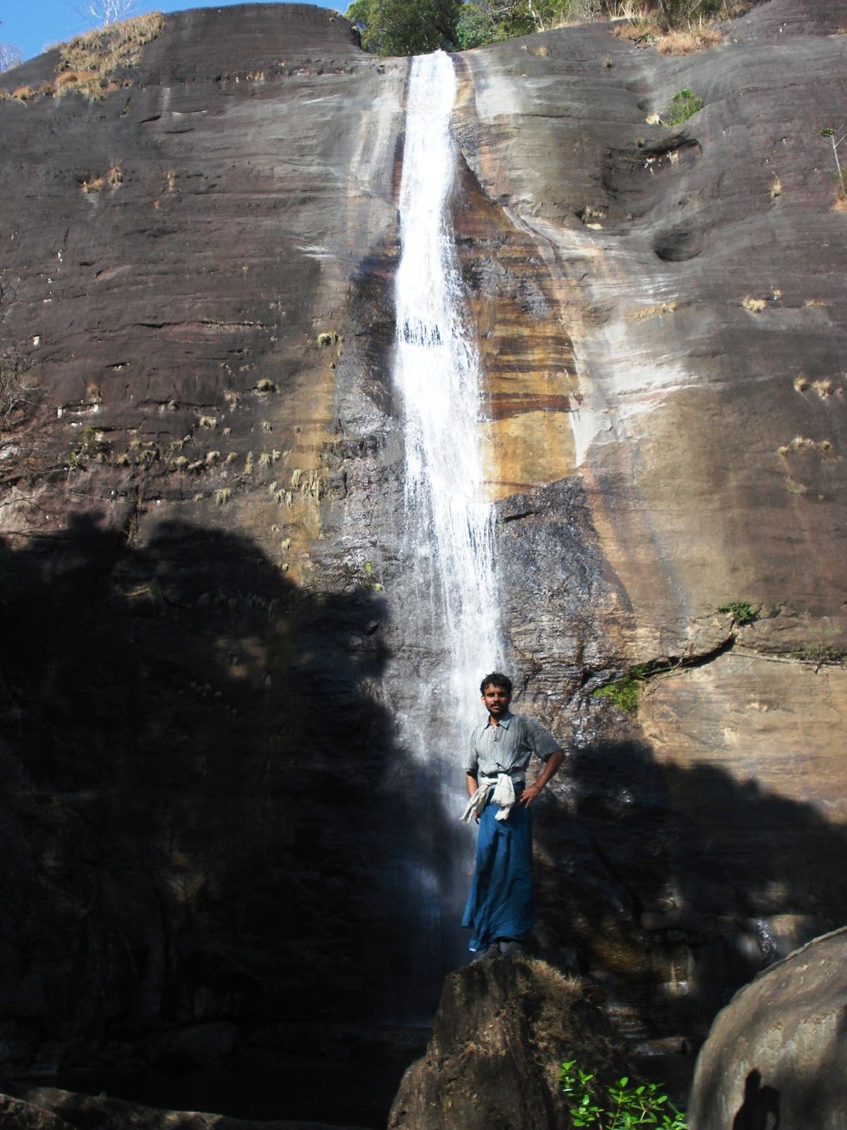 a man standing on the rocks below a waterfall