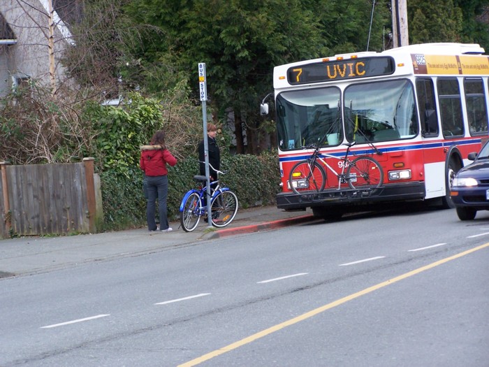 man waiting at bus stop with bicycle and bus