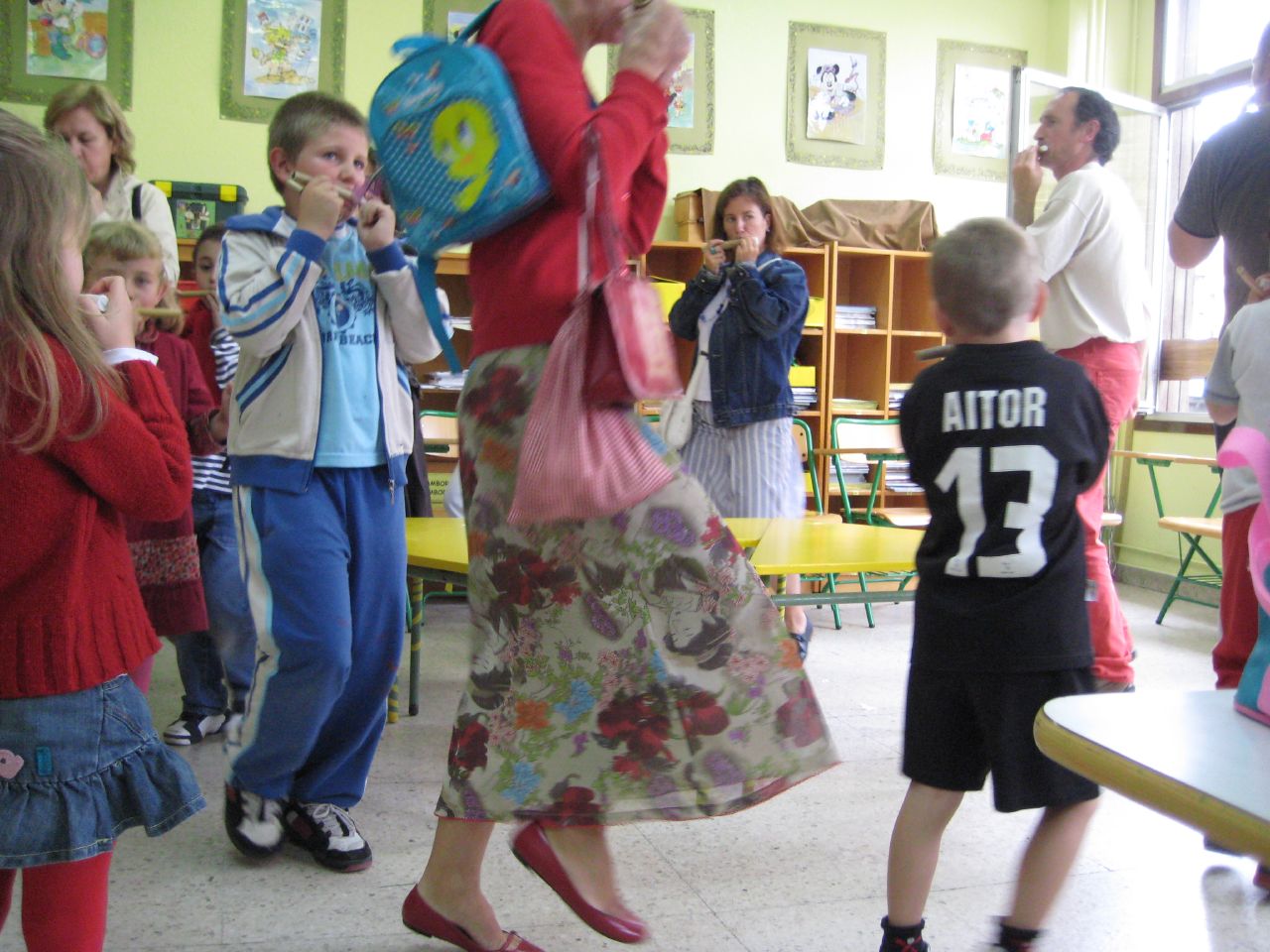 children and an adult watching a group of people with bags