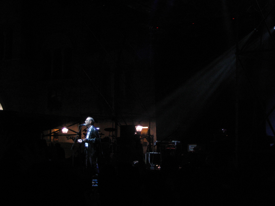 a woman in white jacket playing a guitar at night