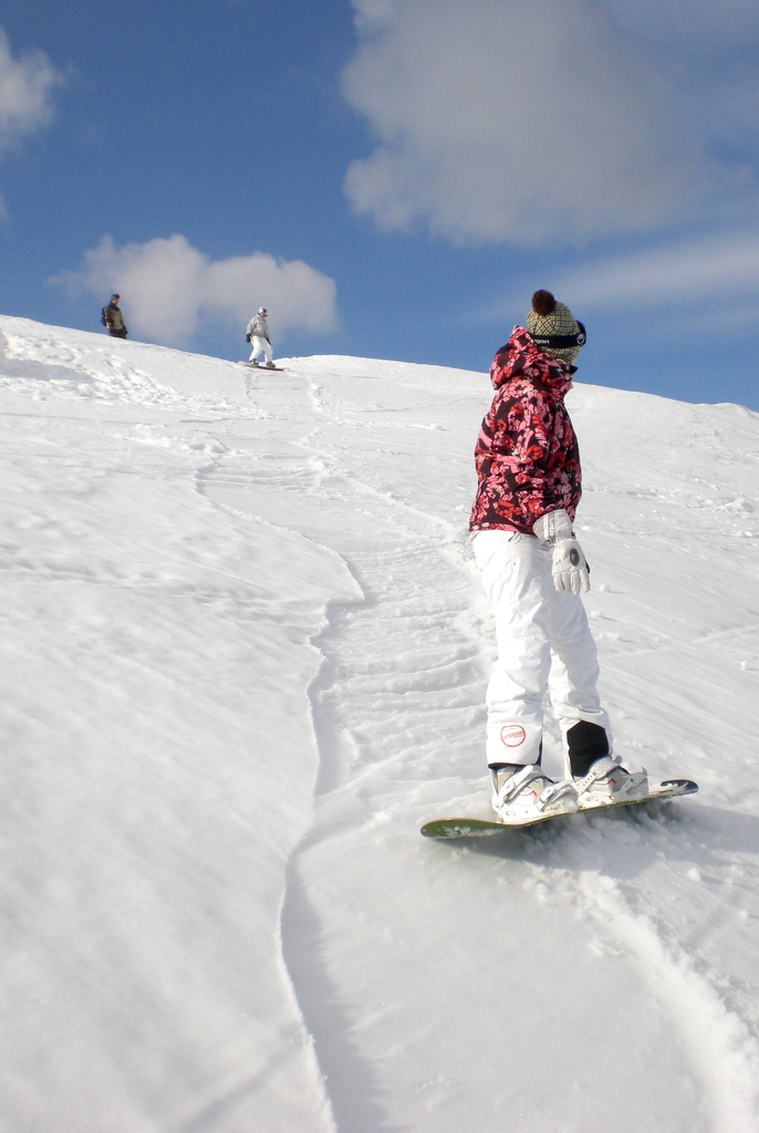 a man in a red and white jacket on a snowboard