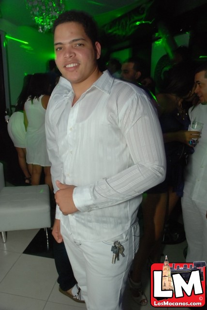 a man standing in white pants and white shirt smiling at the camera