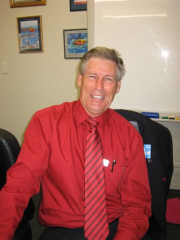 man sitting in an office wearing a red shirt and tie