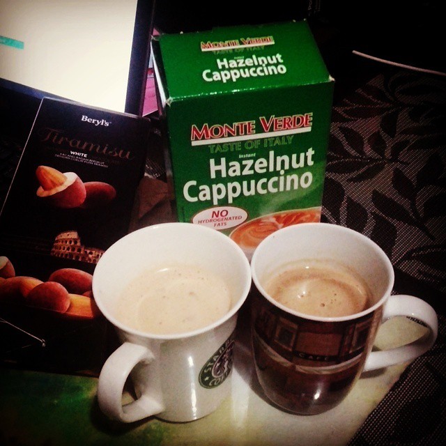 two cups on a table next to a box of hazelnut cappuccino