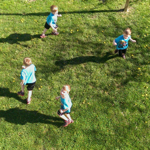 three little boys in the grass playing with soing