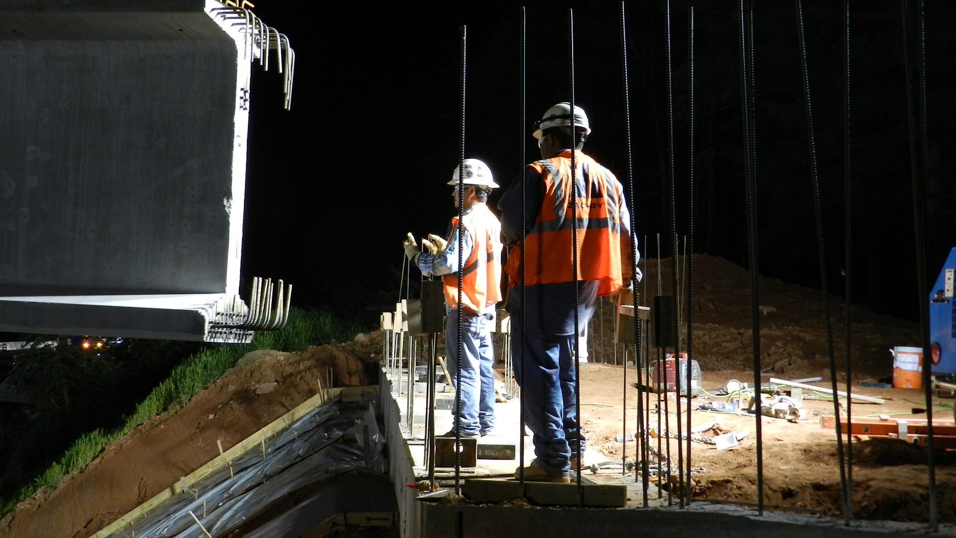 two construction workers looking out onto the night