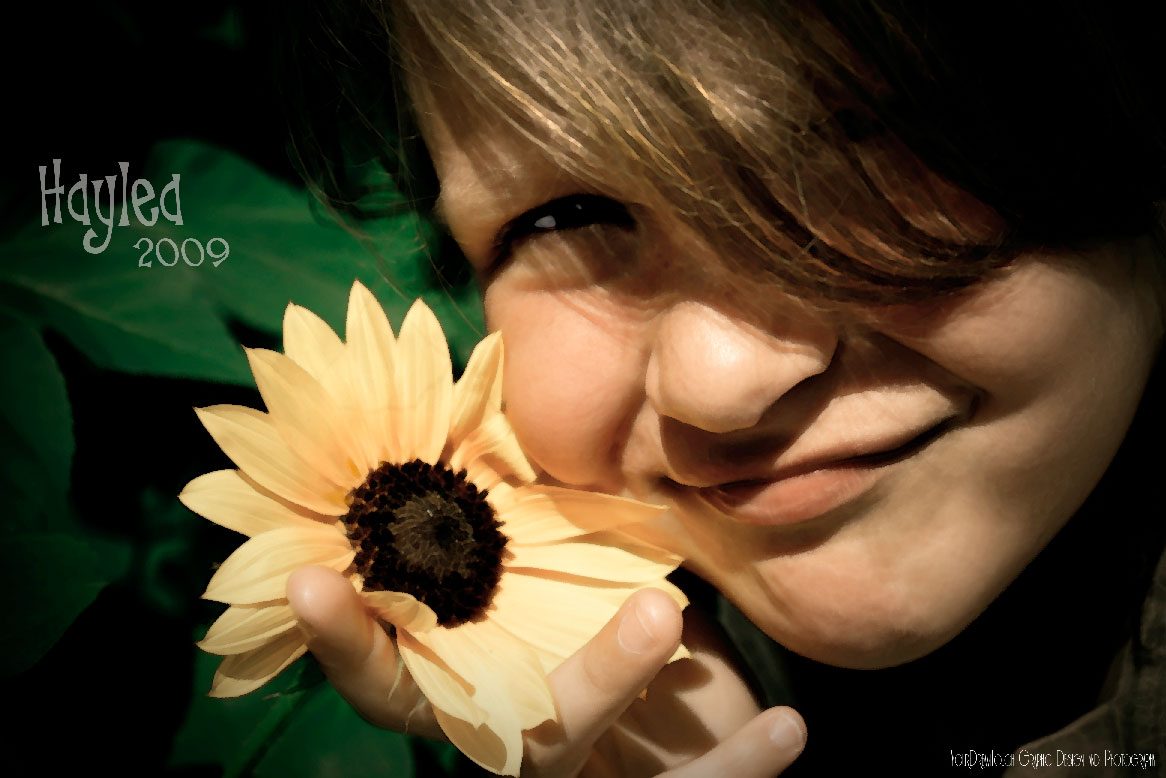 an artistic portrait of a little girl holding up a sunflower