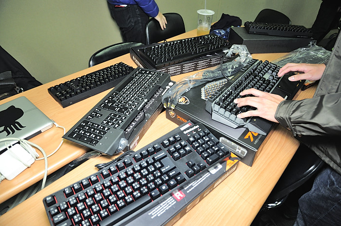 several computer keyboards sitting on a table while people talk to them