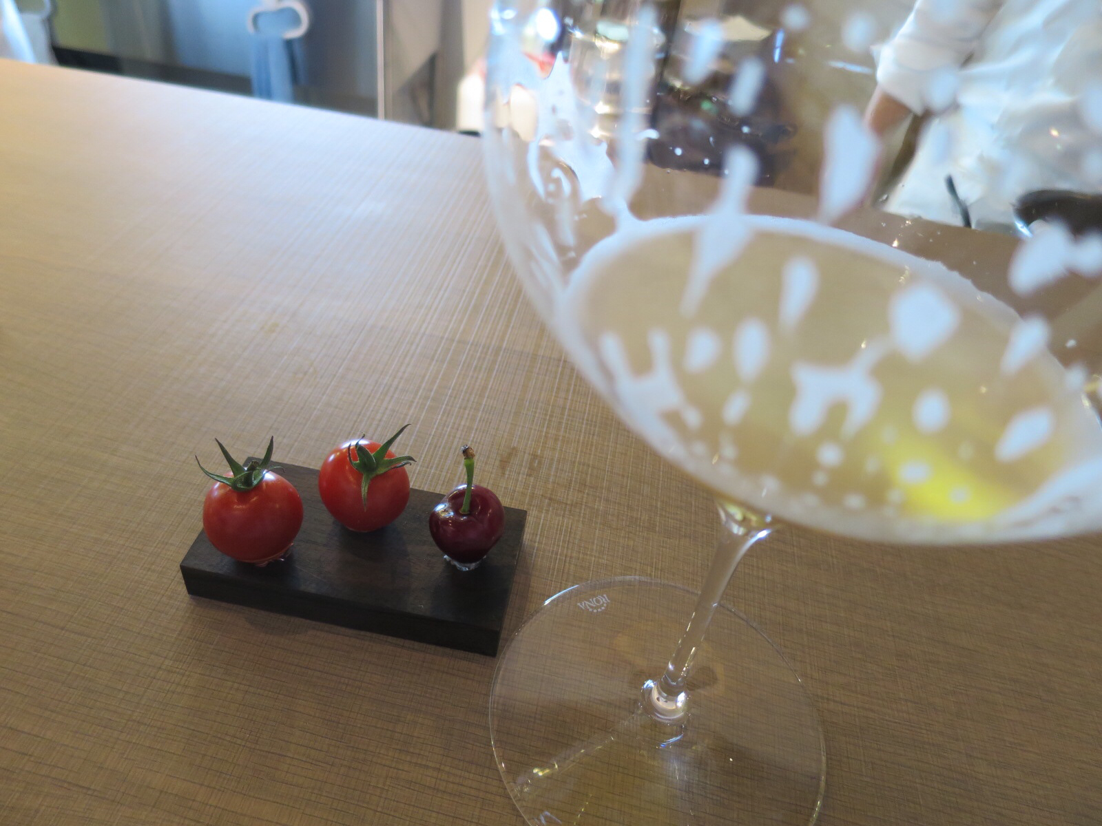 three tomatoes are sitting on a  board and next to a glass