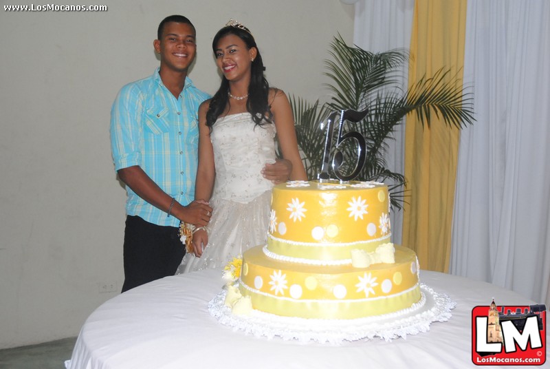 two people in wedding outfits standing in front of a cake