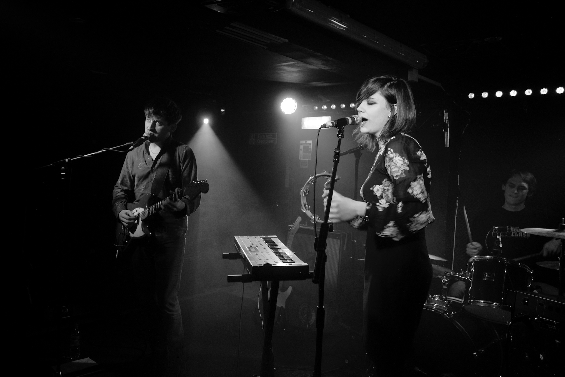 a woman standing on stage next to microphone and keyboard