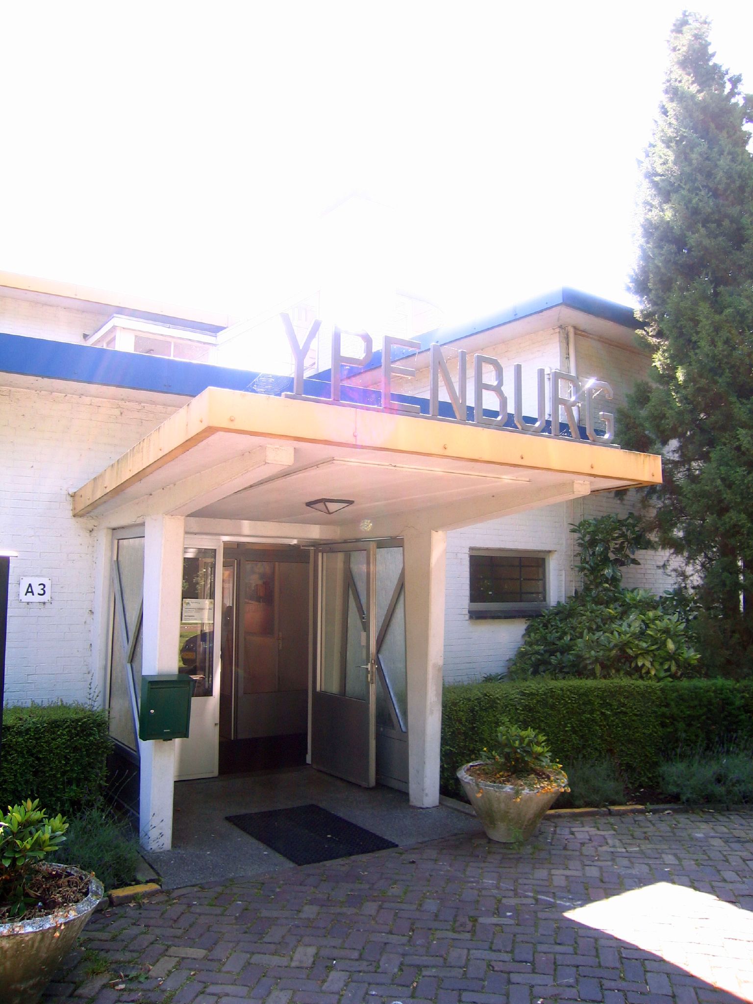 a building with a white brick courtyard and a blue top that has plants around it