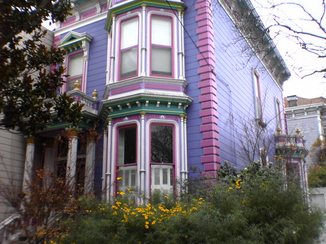 a pink house with purple trim and yellow flowers in front