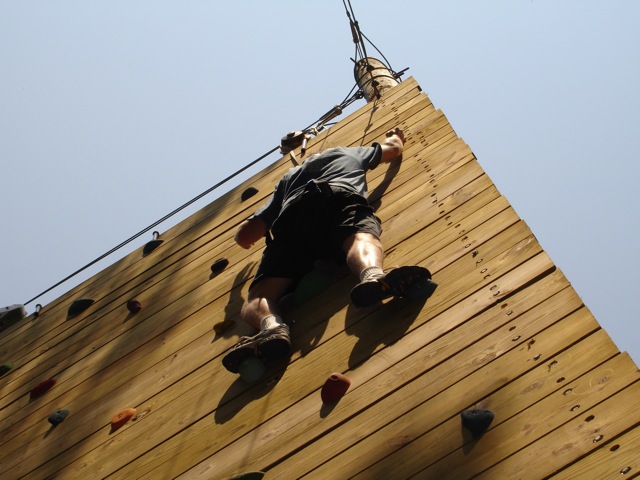 a man on a climb is climbing a wooden wall