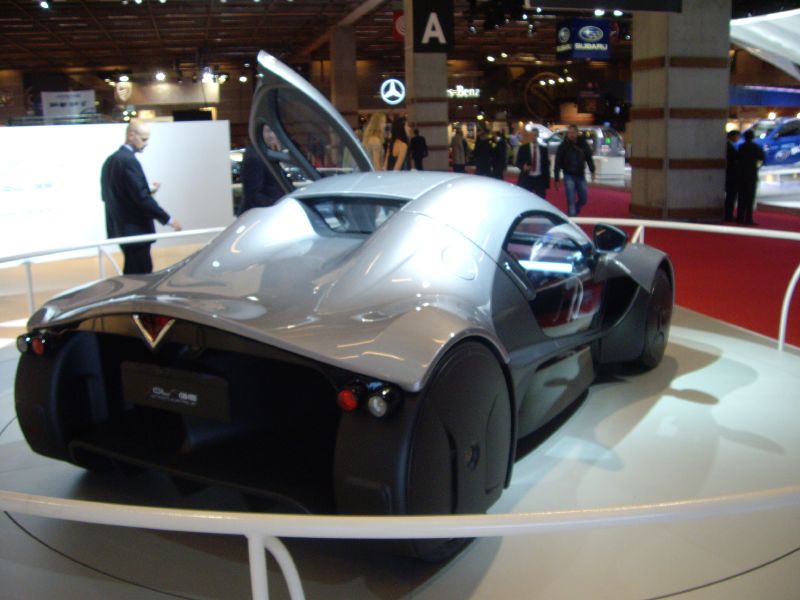 a very shiny black car parked on display at an automobile show