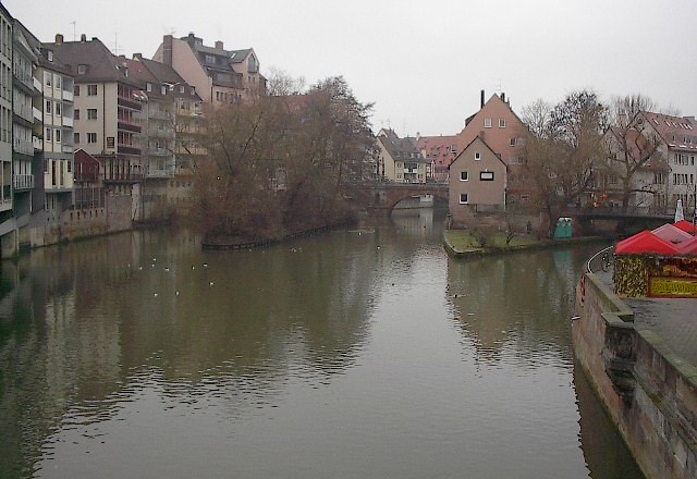 a river with some buildings and a bench on it