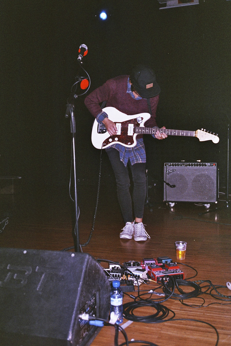 a young man holding a white guitar with one hand