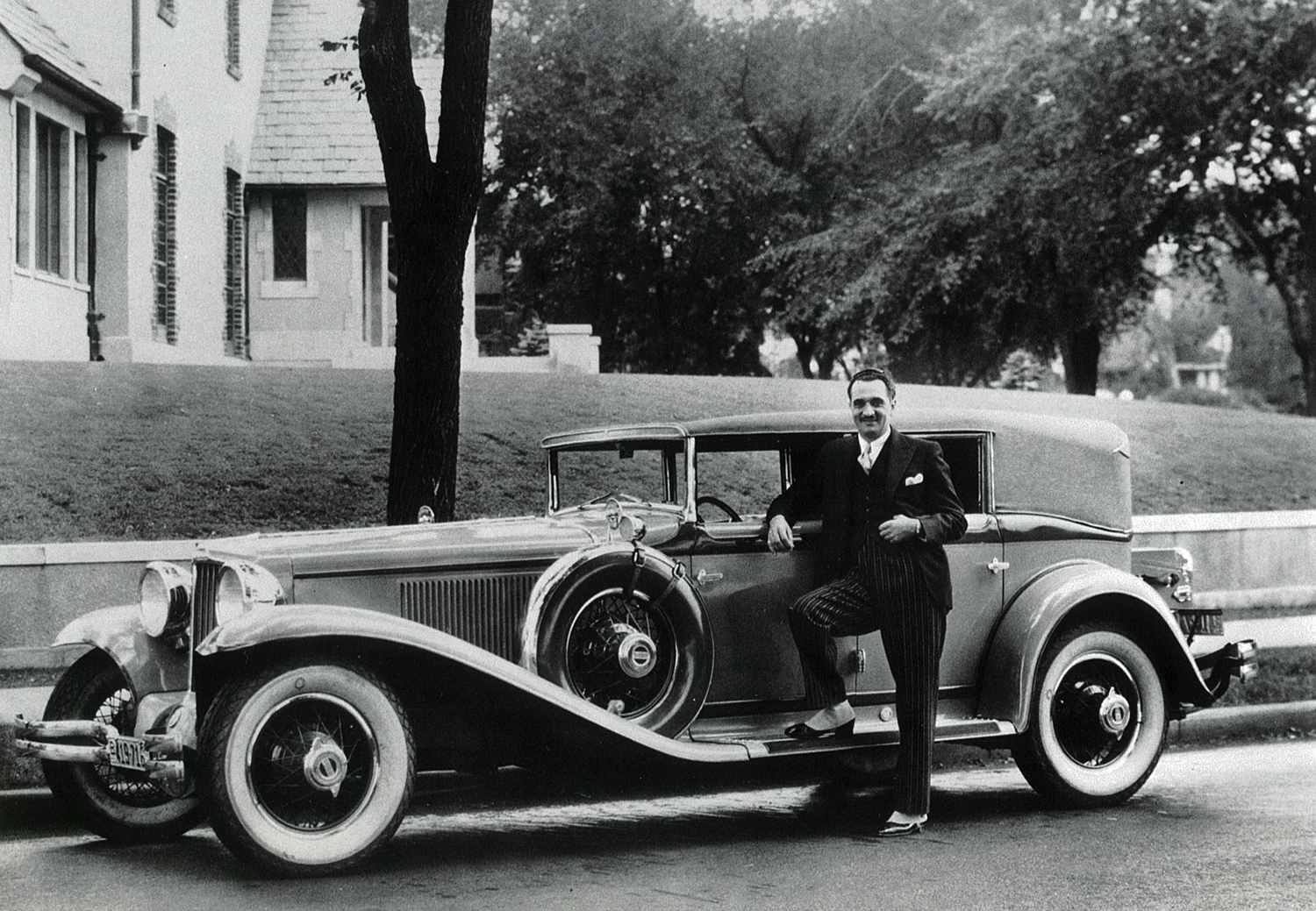 an old po of a man standing next to a car