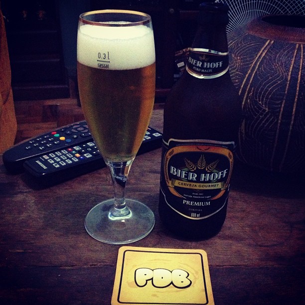 a beer in a glass, a beverage on a table with tv remotes