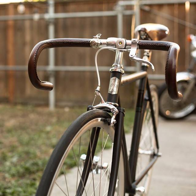 the bicycle is leaning against the wood fence