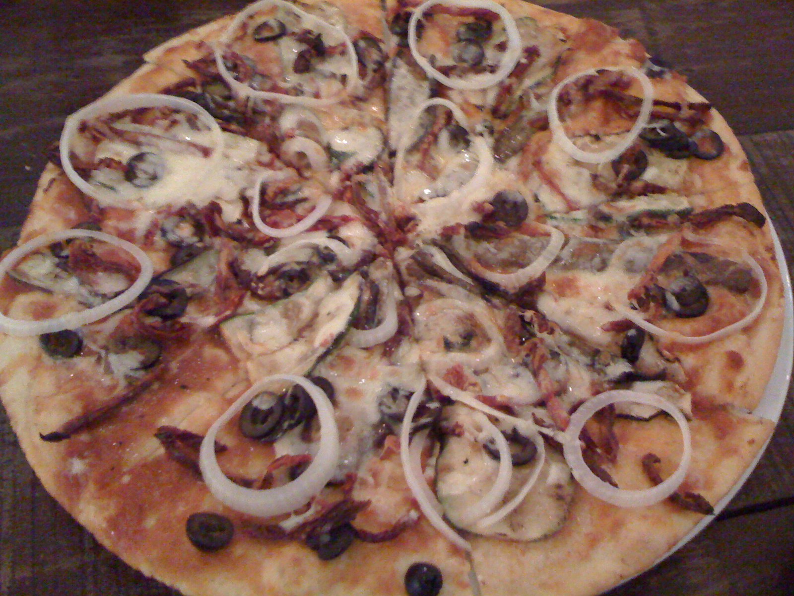 the cooked pizza has onions and black olives