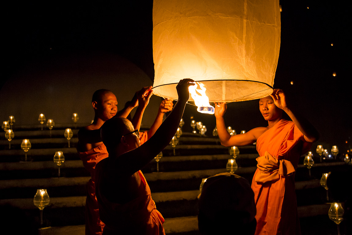 two monks lighting a lamp up into the sky