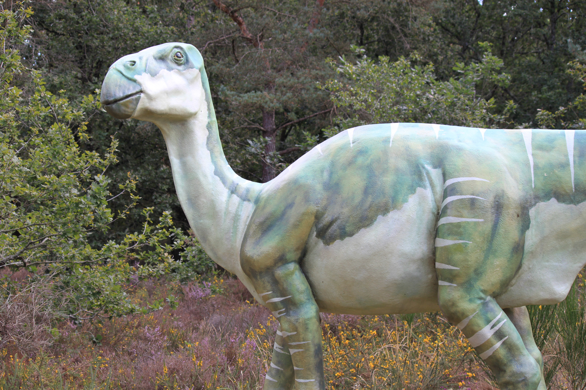 a white and green statue of a camel in a forest