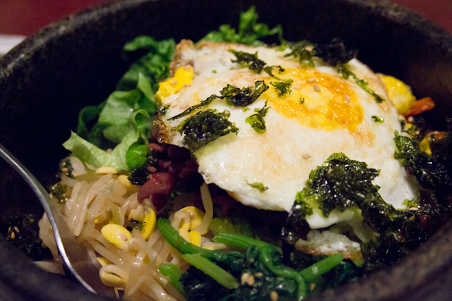 the salad is covered with green vegetables, eggs and noodles
